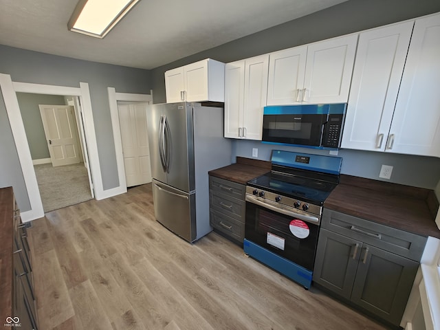 kitchen featuring light hardwood / wood-style floors, butcher block counters, white cabinetry, and appliances with stainless steel finishes