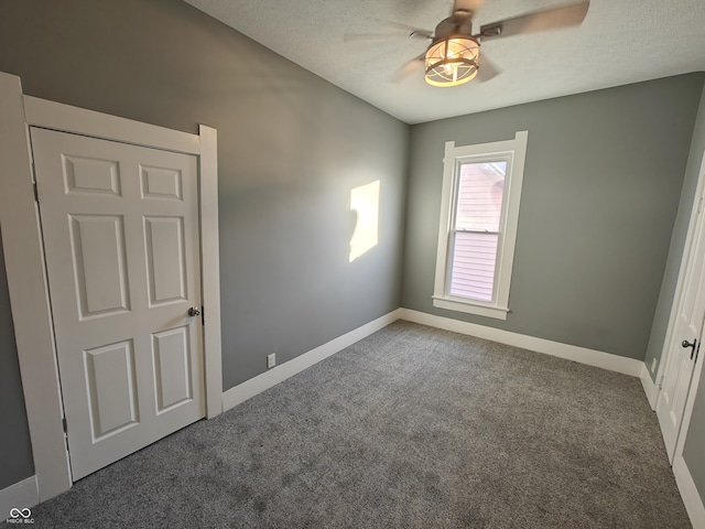 carpeted spare room with a textured ceiling and ceiling fan