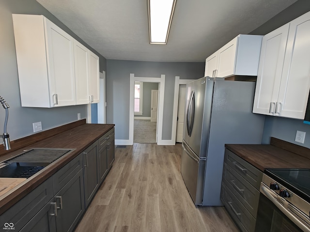 kitchen with light hardwood / wood-style floors, white cabinetry, stainless steel appliances, and wooden counters