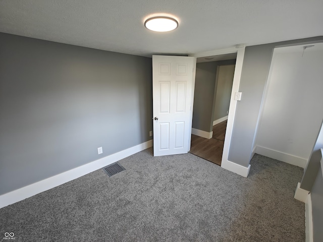 unfurnished bedroom with dark carpet and a textured ceiling