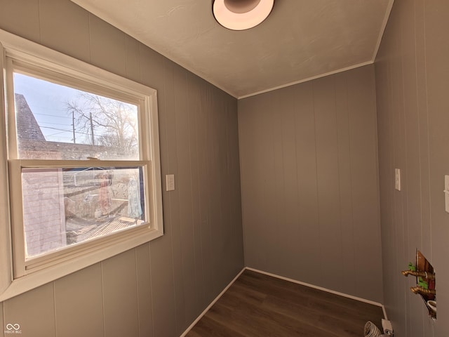 empty room featuring dark hardwood / wood-style flooring, crown molding, and wooden walls