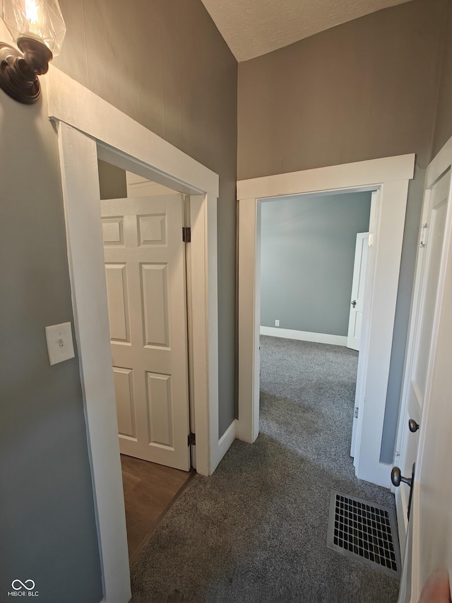 hallway featuring dark carpet