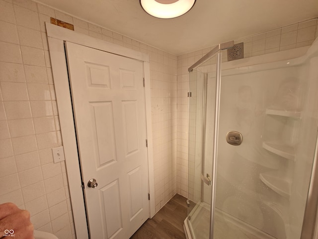 bathroom featuring hardwood / wood-style flooring, walk in shower, and tile walls