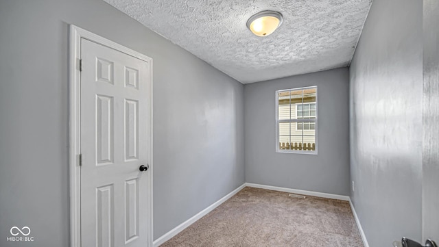 carpeted empty room with a textured ceiling