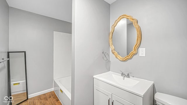 bathroom with toilet, vanity, and hardwood / wood-style flooring