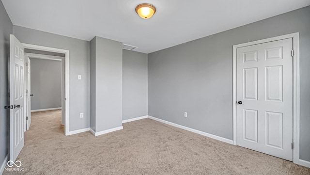 unfurnished bedroom featuring light carpet and a closet