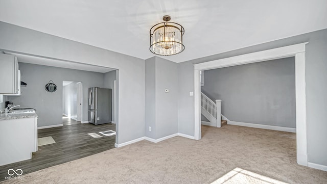 carpeted empty room with sink and an inviting chandelier