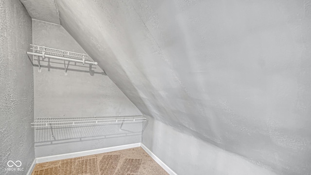 walk in closet featuring carpet floors and lofted ceiling