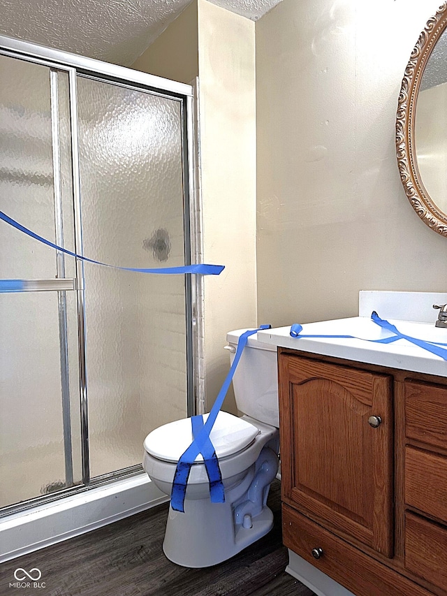 bathroom featuring hardwood / wood-style floors, vanity, toilet, a textured ceiling, and an enclosed shower