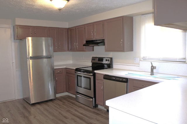 kitchen with light hardwood / wood-style flooring, stainless steel appliances, a textured ceiling, and sink