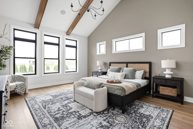 bedroom with a notable chandelier, light hardwood / wood-style floors, high vaulted ceiling, and multiple windows