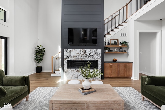 living room with a towering ceiling, hardwood / wood-style flooring, and a premium fireplace