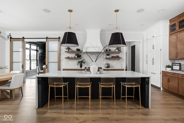 kitchen featuring a large island with sink, a barn door, dark hardwood / wood-style flooring, and pendant lighting