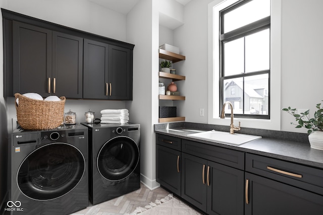 clothes washing area featuring washer and dryer, sink, light parquet floors, and cabinets