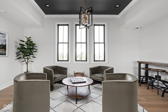 living room featuring hardwood / wood-style flooring, crown molding, and an inviting chandelier