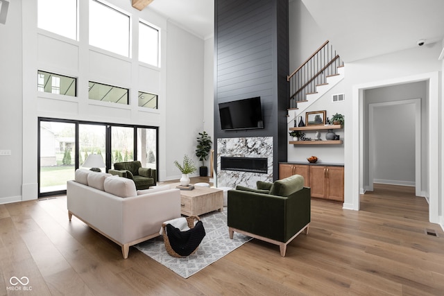 living room featuring a high end fireplace, a high ceiling, and hardwood / wood-style flooring