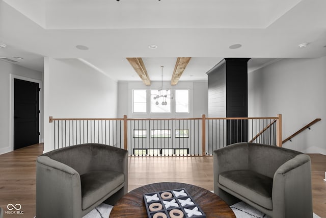 sitting room featuring beamed ceiling, wood-type flooring, and a notable chandelier