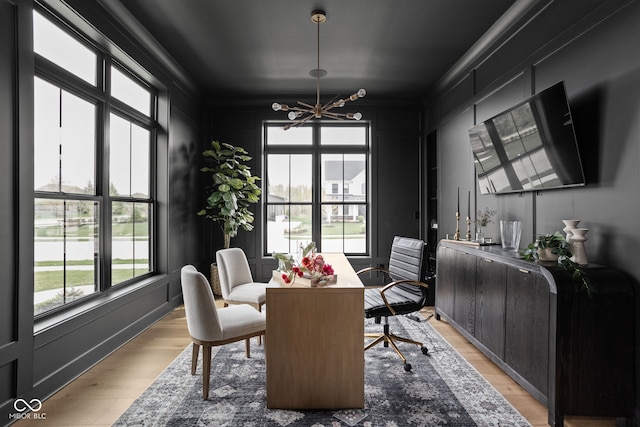 dining space with an inviting chandelier, ornamental molding, and light hardwood / wood-style flooring