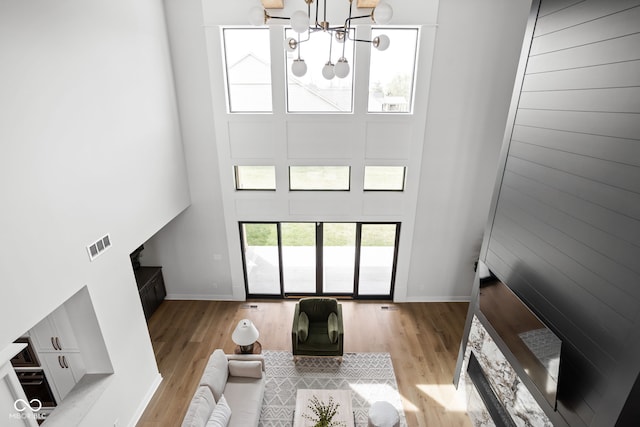 living room featuring a chandelier, a high ceiling, and light hardwood / wood-style flooring