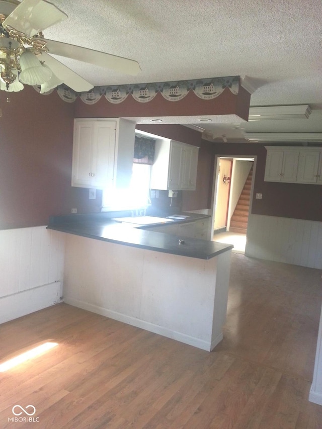 kitchen featuring hardwood / wood-style flooring, kitchen peninsula, and white cabinets