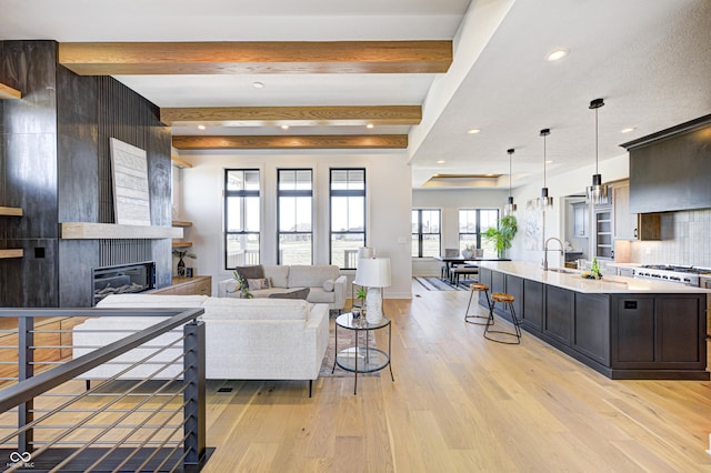 living room with a large fireplace, light hardwood / wood-style flooring, and beamed ceiling