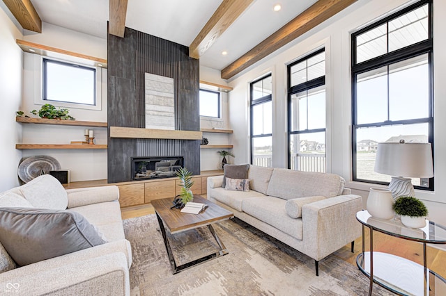 living room with a fireplace, plenty of natural light, and beamed ceiling