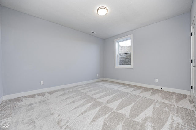 empty room with light colored carpet and a textured ceiling