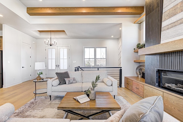 living room with beam ceiling, a chandelier, and light hardwood / wood-style floors