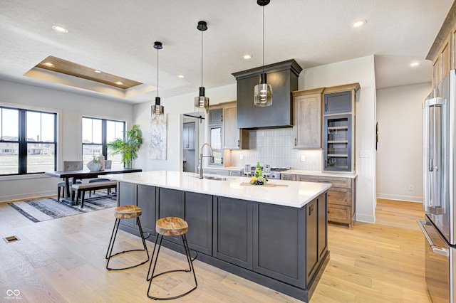 kitchen with pendant lighting, a center island with sink, light hardwood / wood-style flooring, and appliances with stainless steel finishes