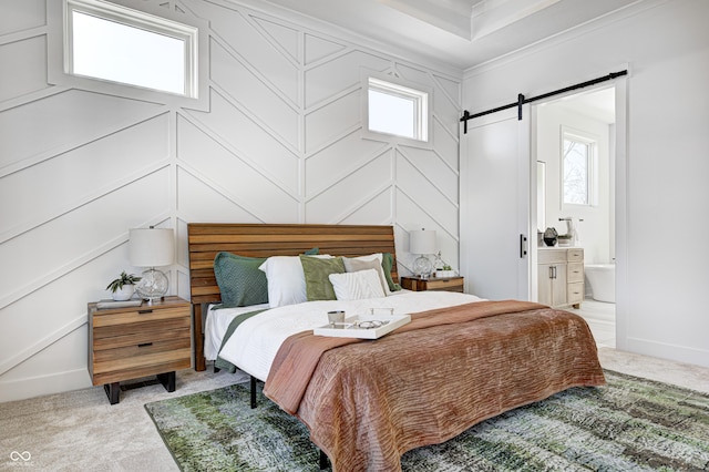 bedroom featuring a barn door, light colored carpet, multiple windows, and ensuite bath