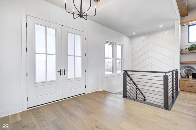 foyer featuring beamed ceiling, french doors, light hardwood / wood-style flooring, and a notable chandelier