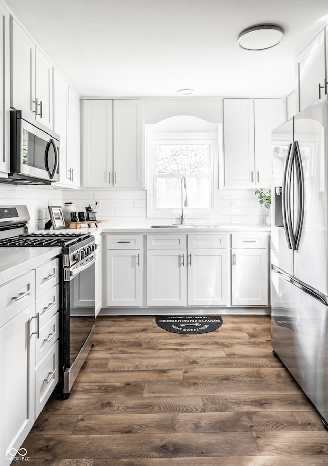 kitchen featuring white cabinets, appliances with stainless steel finishes, dark hardwood / wood-style floors, and sink