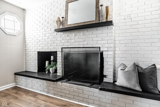 interior details featuring wood-type flooring and a brick fireplace