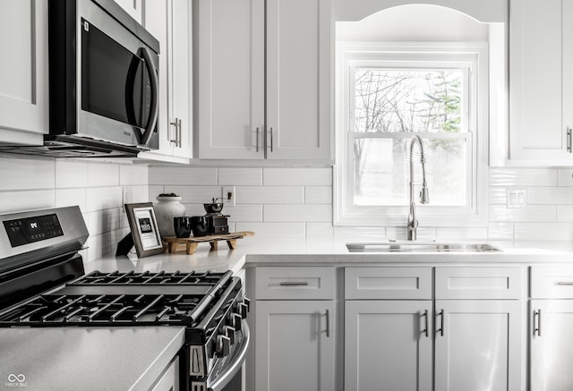 kitchen with decorative backsplash, white cabinetry, sink, and appliances with stainless steel finishes