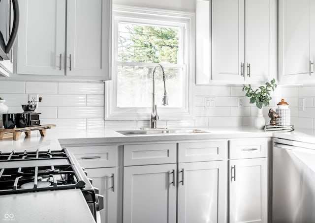 kitchen featuring tasteful backsplash, white cabinetry, sink, and appliances with stainless steel finishes