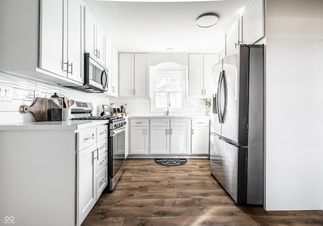 kitchen with dark wood-type flooring, white cabinets, sink, decorative backsplash, and stainless steel appliances