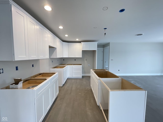 kitchen with wood-type flooring, a center island, and white cabinets