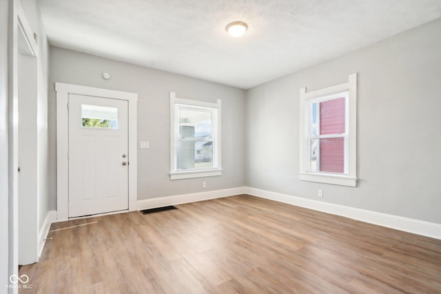 foyer entrance with light hardwood / wood-style flooring and a textured ceiling