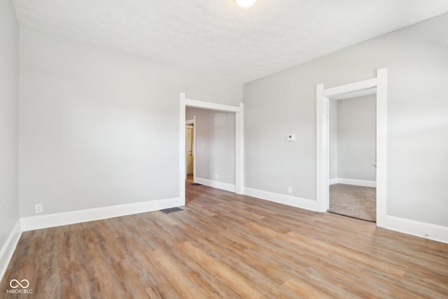 unfurnished room featuring a textured ceiling and light hardwood / wood-style flooring