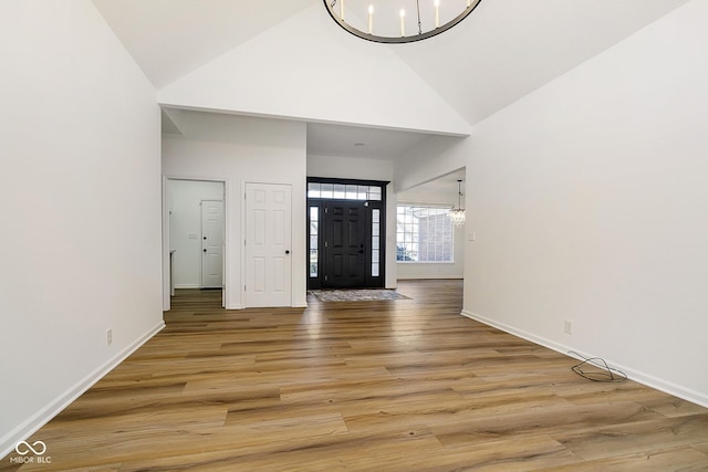 foyer entrance featuring high vaulted ceiling, an inviting chandelier, and hardwood / wood-style flooring