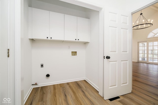 washroom featuring hookup for a gas dryer, cabinets, light hardwood / wood-style floors, hookup for a washing machine, and a chandelier