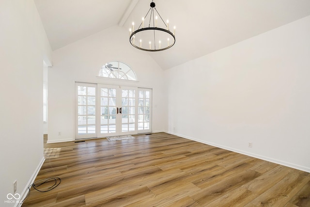 unfurnished room with hardwood / wood-style flooring, beam ceiling, french doors, and ceiling fan with notable chandelier