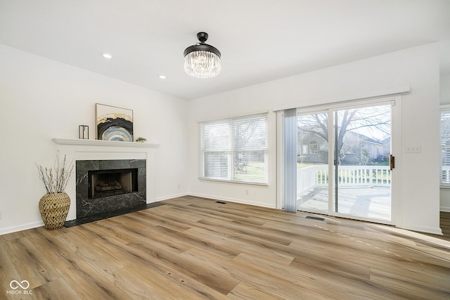 unfurnished living room with a high end fireplace, a chandelier, and hardwood / wood-style flooring