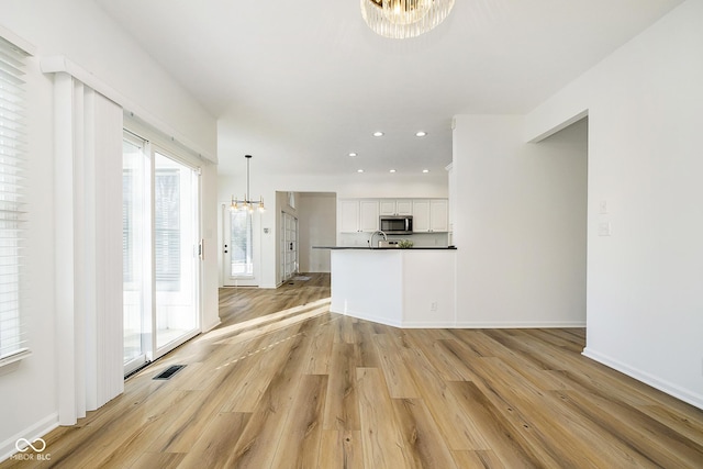 unfurnished living room featuring light hardwood / wood-style floors, sink, and a chandelier