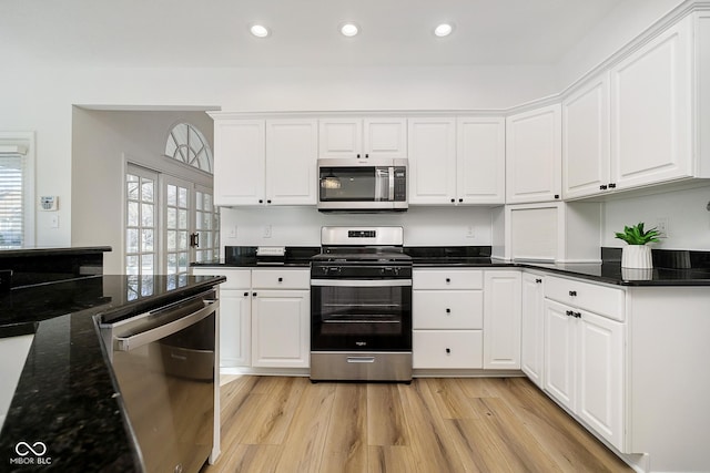 kitchen featuring white cabinets, appliances with stainless steel finishes, french doors, dark stone countertops, and light wood-type flooring