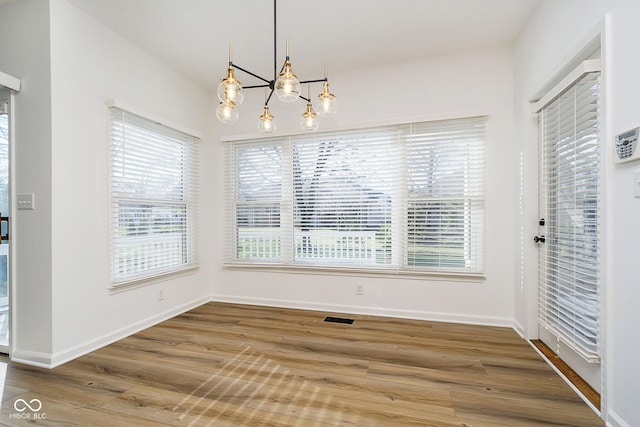 unfurnished dining area featuring hardwood / wood-style floors and a chandelier