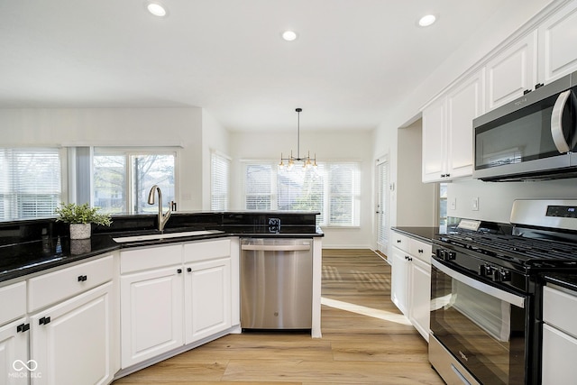 kitchen with white cabinets, appliances with stainless steel finishes, sink, and a chandelier