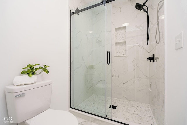 bathroom featuring toilet and a shower with shower door