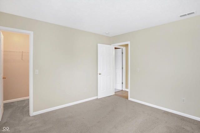 unfurnished bedroom with a walk in closet, carpet floors, and a closet