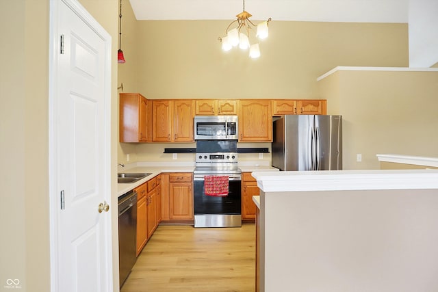 kitchen featuring light wood-type flooring, stainless steel appliances, sink, decorative light fixtures, and an inviting chandelier